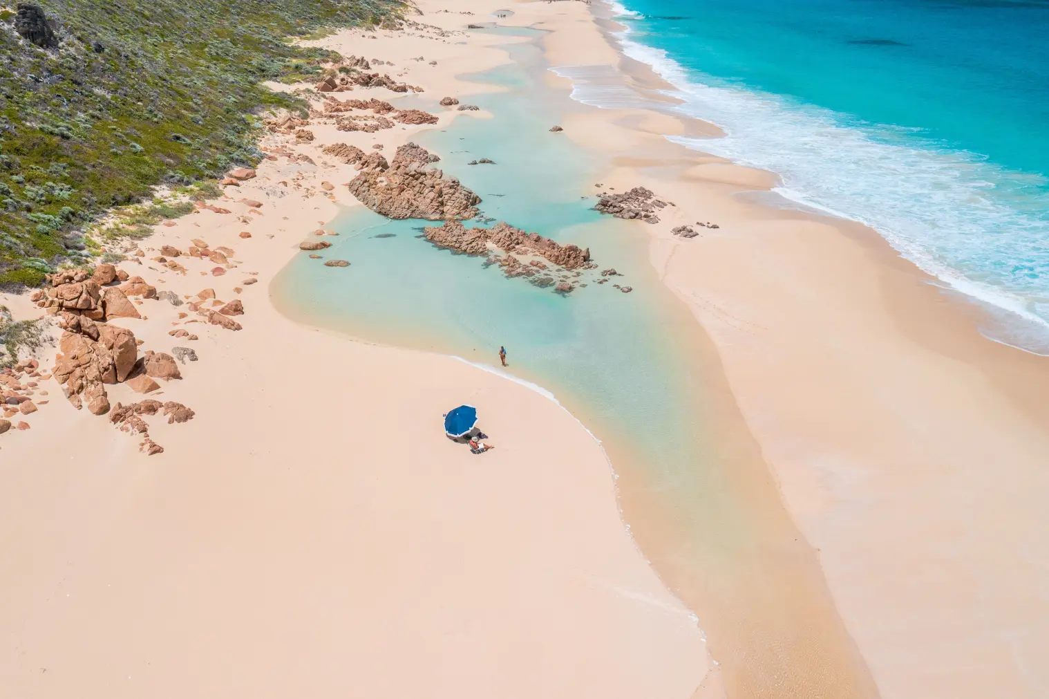 Secluded beach with a person under blue umbrella