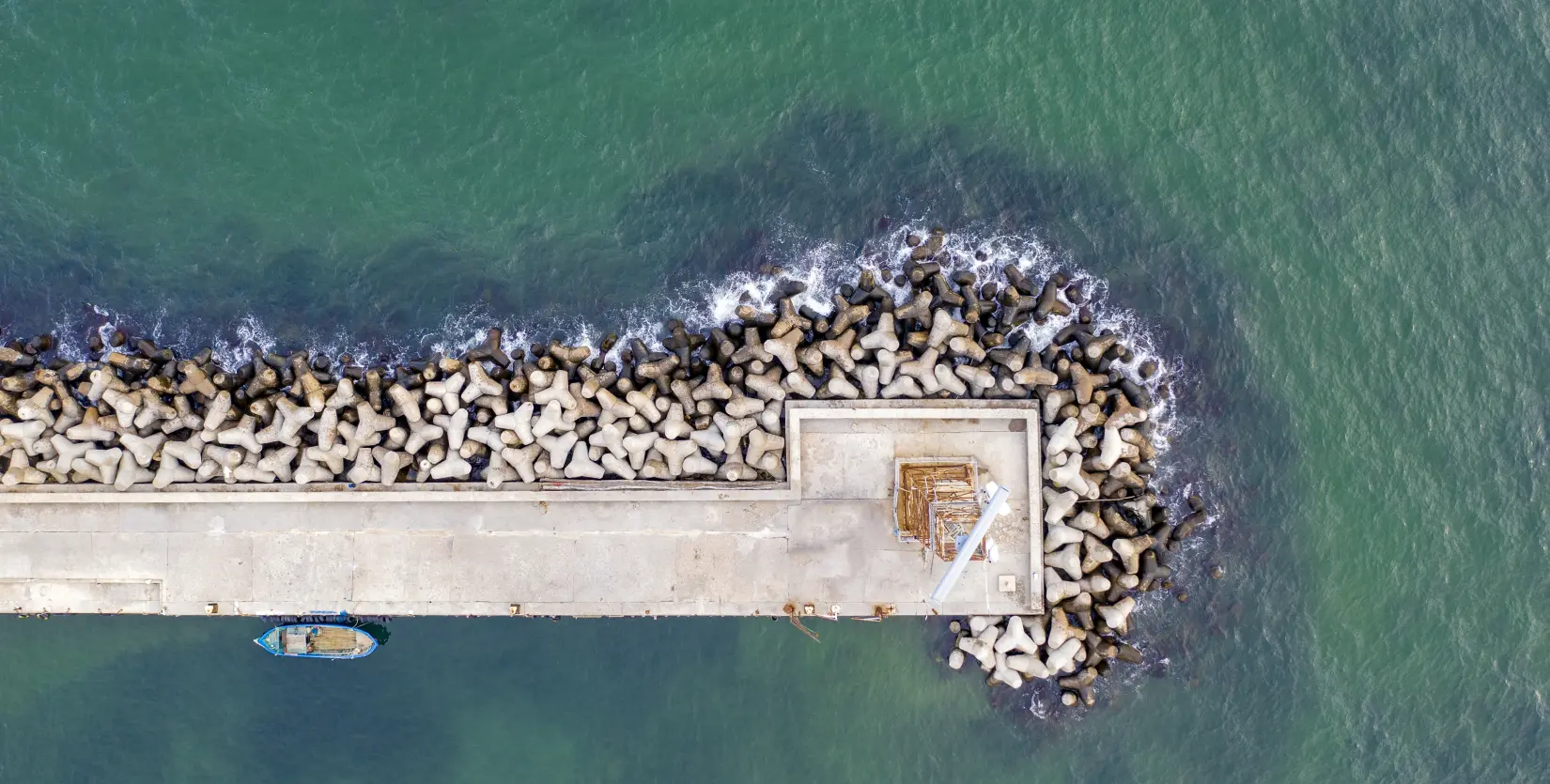 Aerial drone view of concrete breakwater and fishing boat on the ocean