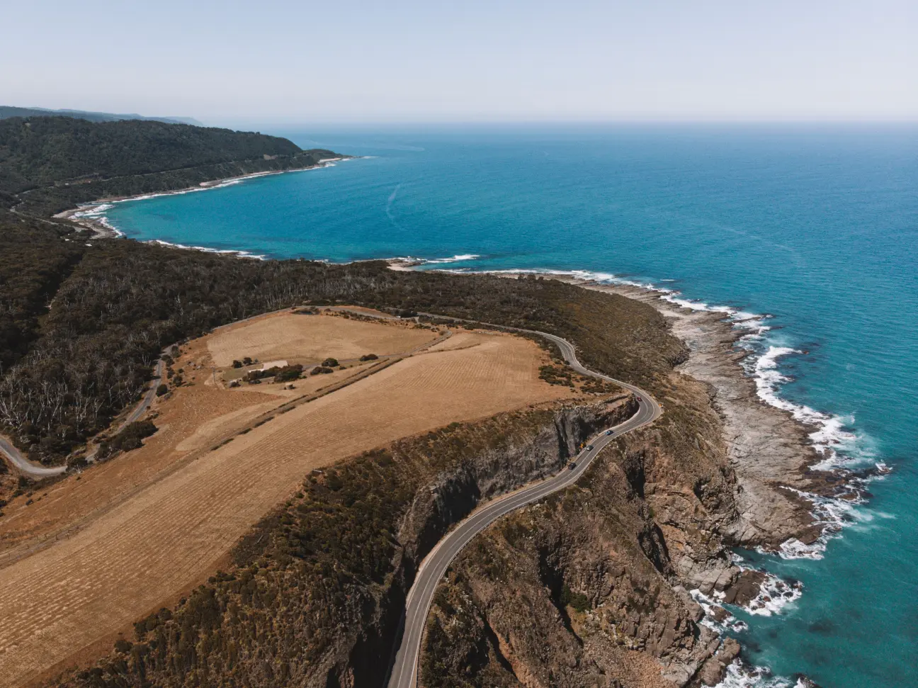 Aerial view of winding coastal road with ocean cliffs