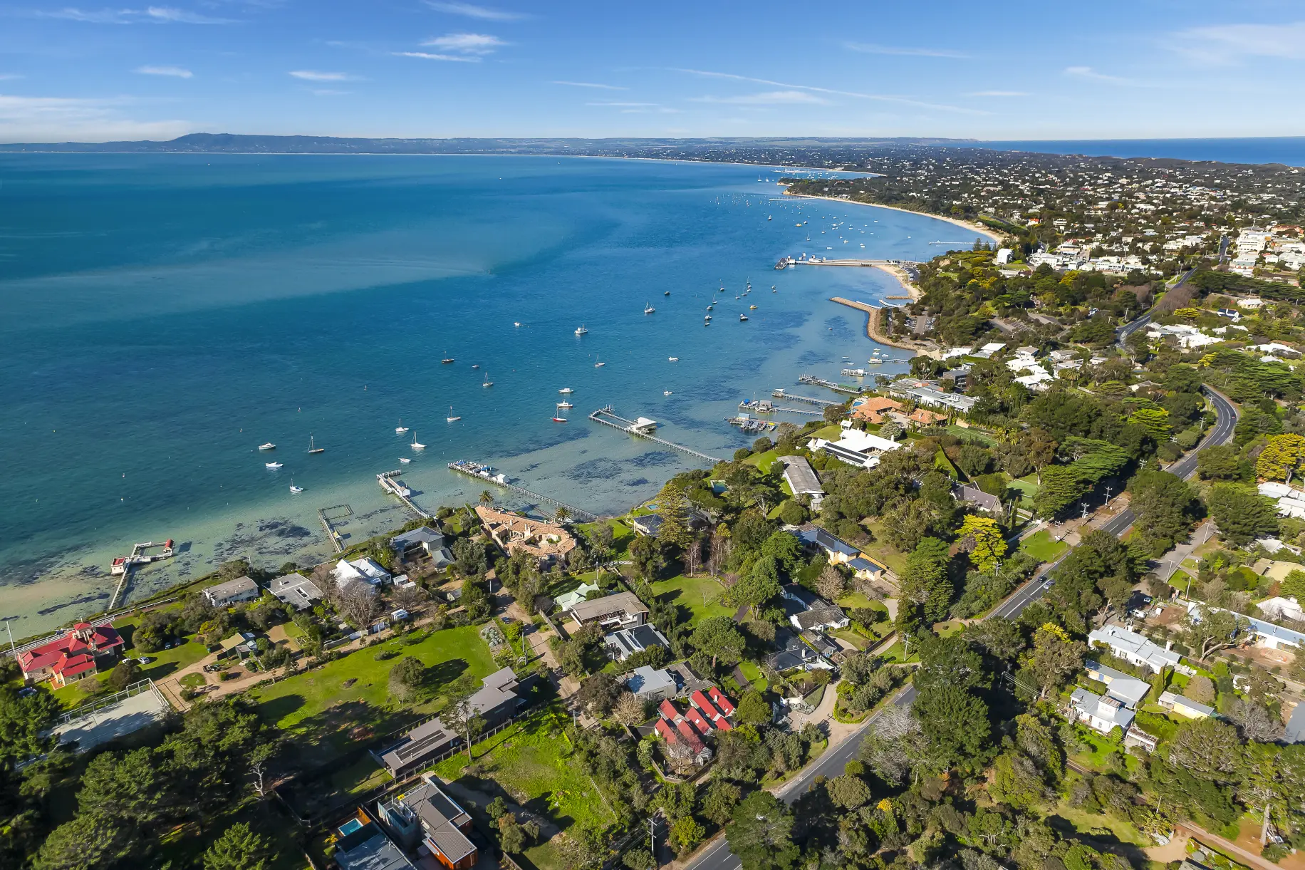 Aerial view of Australian coastline with residential houses and boats on the bay