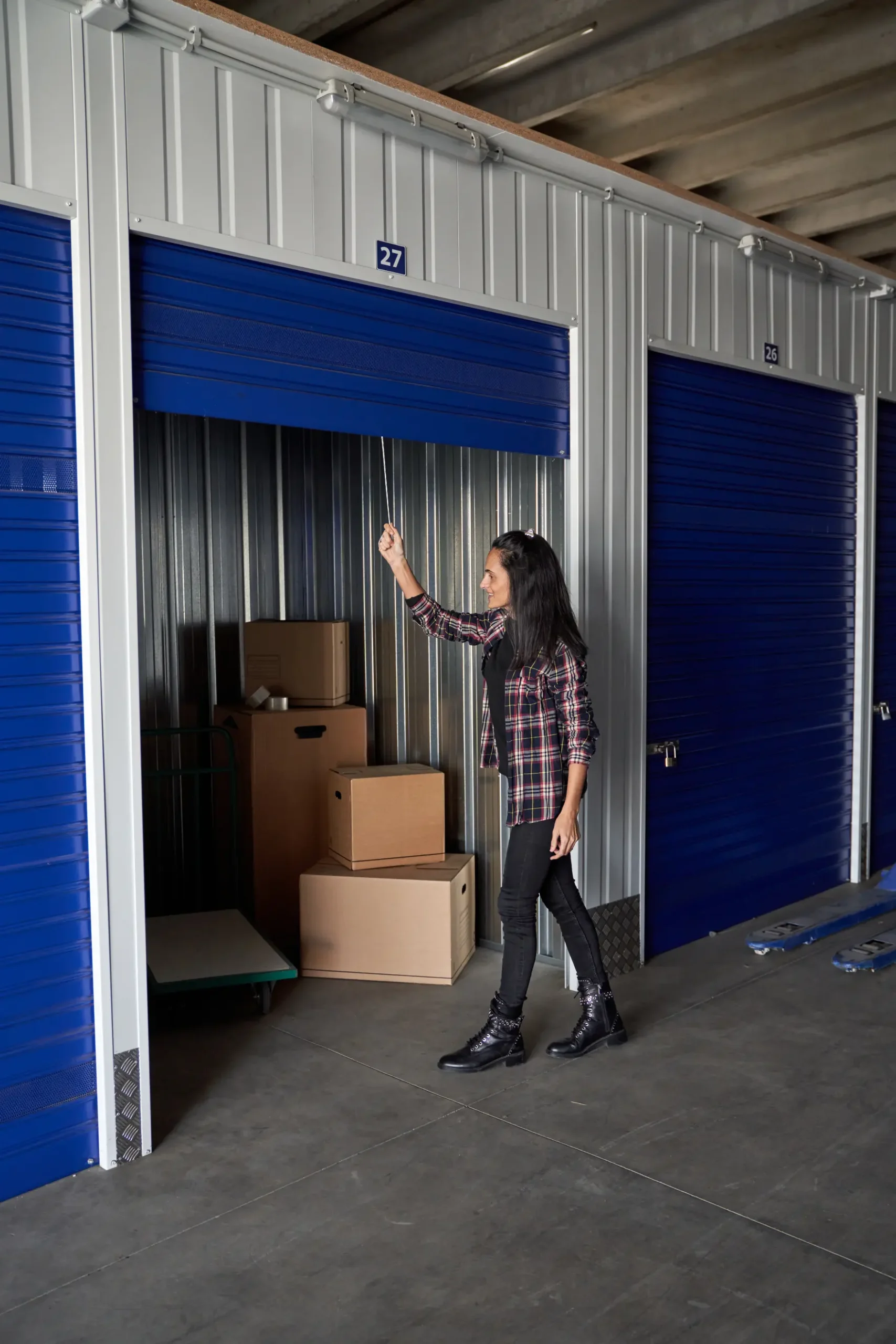 Couple packing moving boxes in a modern living room with open door and stacked cardboard boxes near entryway