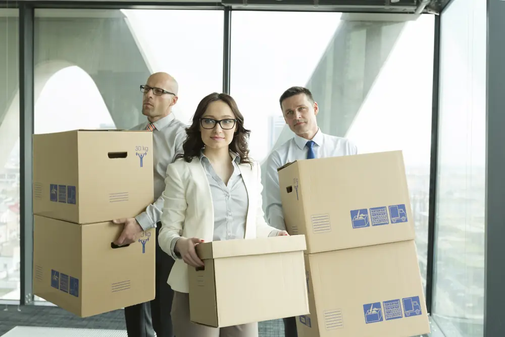 Professional team carrying cardboard boxes during an office relocation with Peninsula Moving in a modern high-rise building