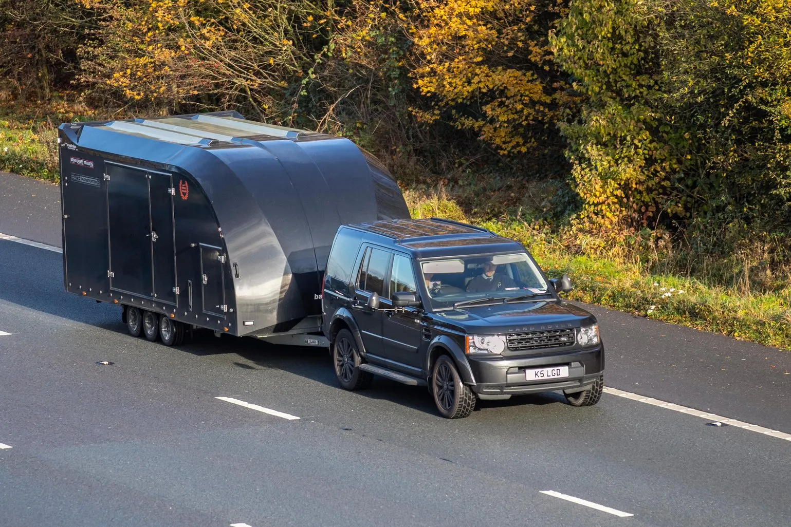Black SUV pulling enclosed car carrier